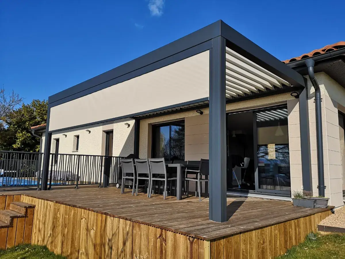 Une terrasse en bois avec une pergola sans emprise au sol, offrant un espace repas extérieur moderne et élégant sous un ciel bleu éclatant.