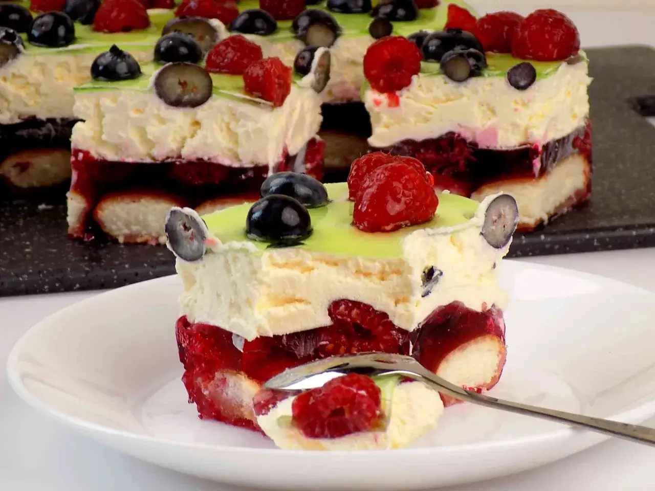 Pyszne ciasto z mascarpone, przełożone malinami i galaretką, ozdobione owocami leśnymi. Idealne na deser!