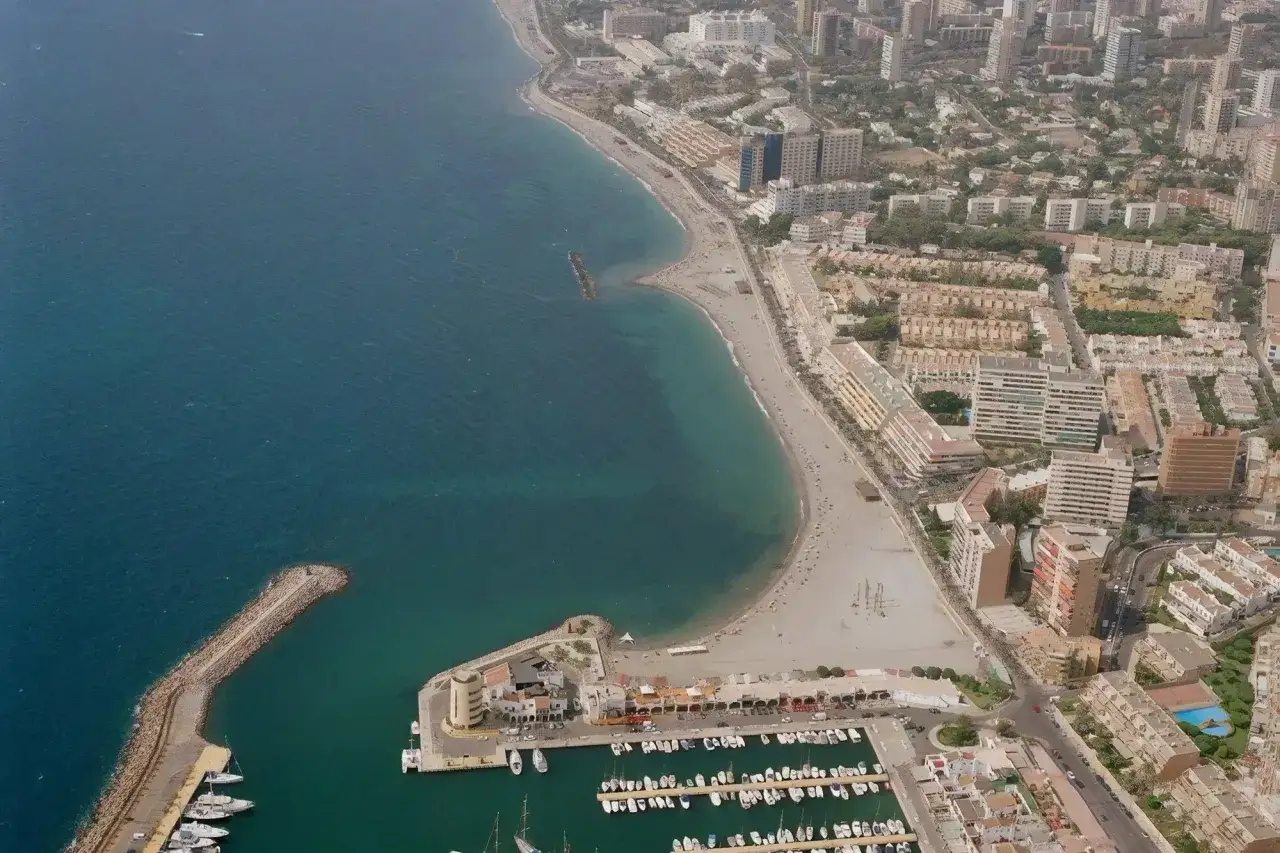 Vista aérea de la playa de Aguadulce con su puerto deportivo lleno de barcos y la costa urbana extendiéndose.
