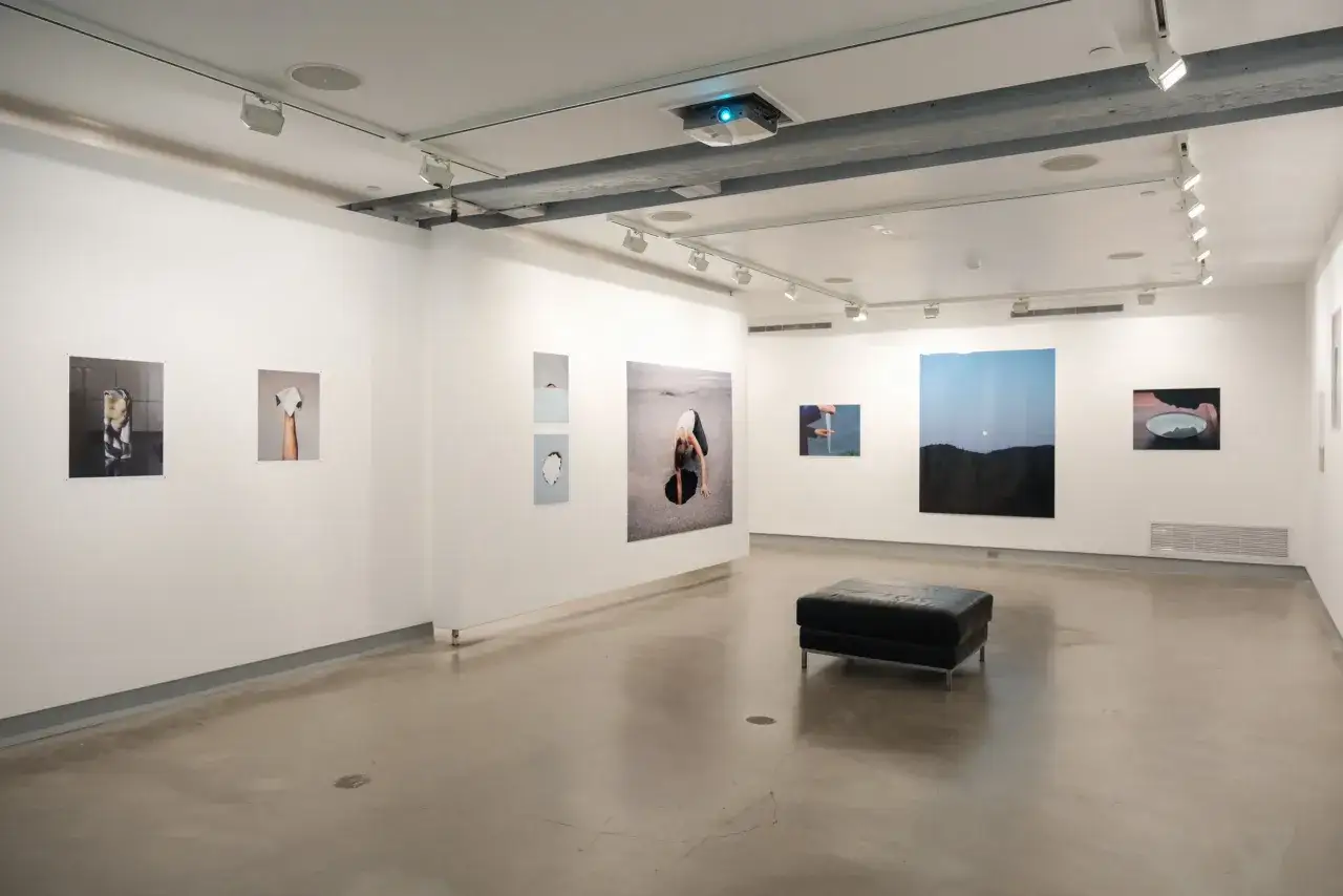 Art exhibition at blue sky gallery portland, featuring diverse photographic works and a black leather ottoman.