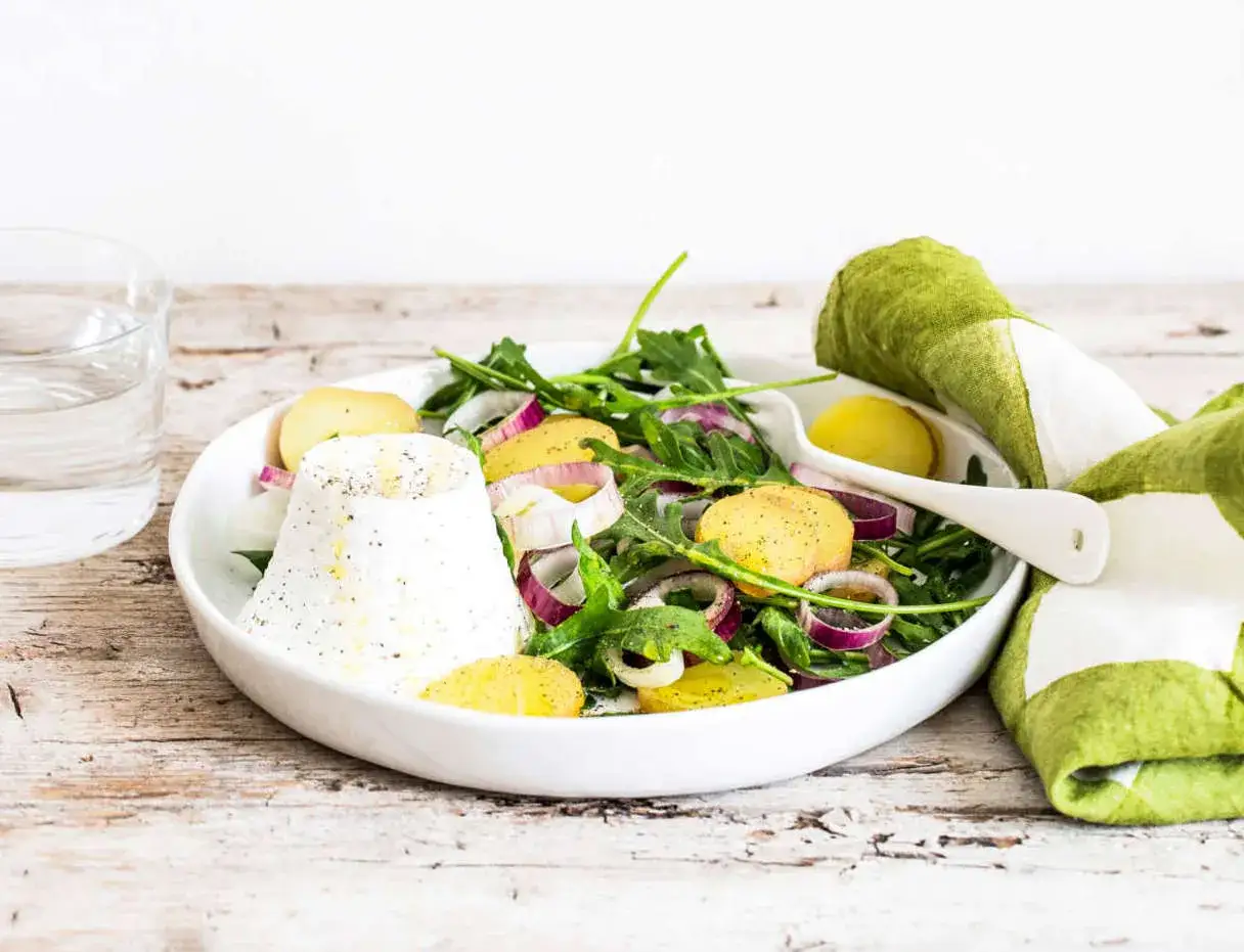 Insalata fresca con ricotta di mucca, patate e cipolla rossa. Un piatto leggero, ideale per chi cerca poche calorie.