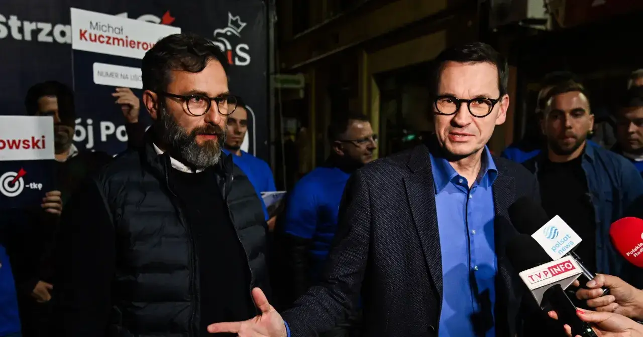 Michał Kuczmierowski i Mateusz Morawiecki przed mikrofonami. Tło sugeruje kampanię wyborczą, być może związaną z listą afer PiS.
