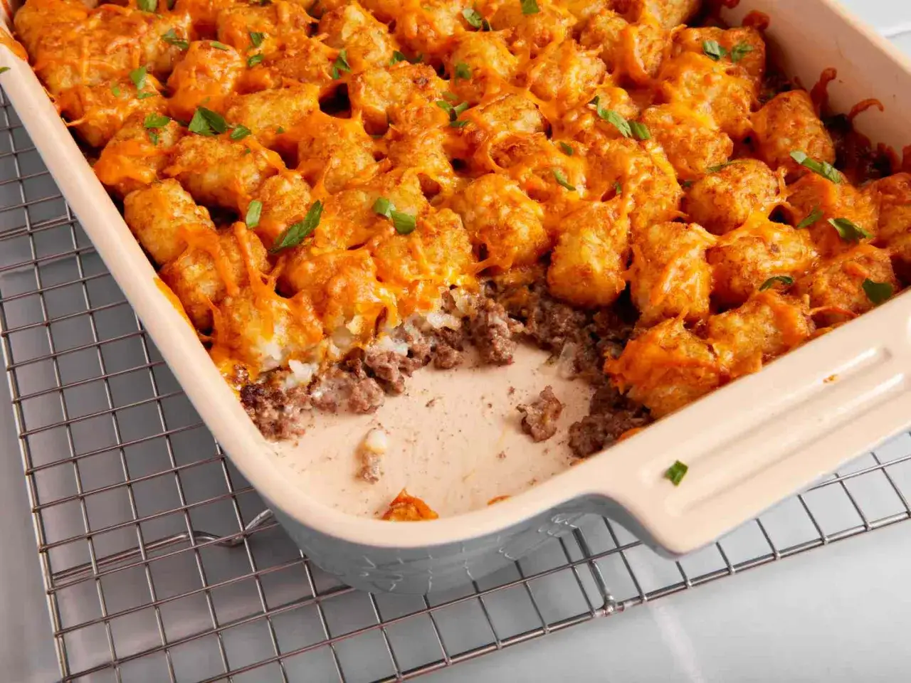 En ugnsform fylld med köttfärs och toppad med gyllene tater tots och smält ost. Garnerad med färsk persilja.