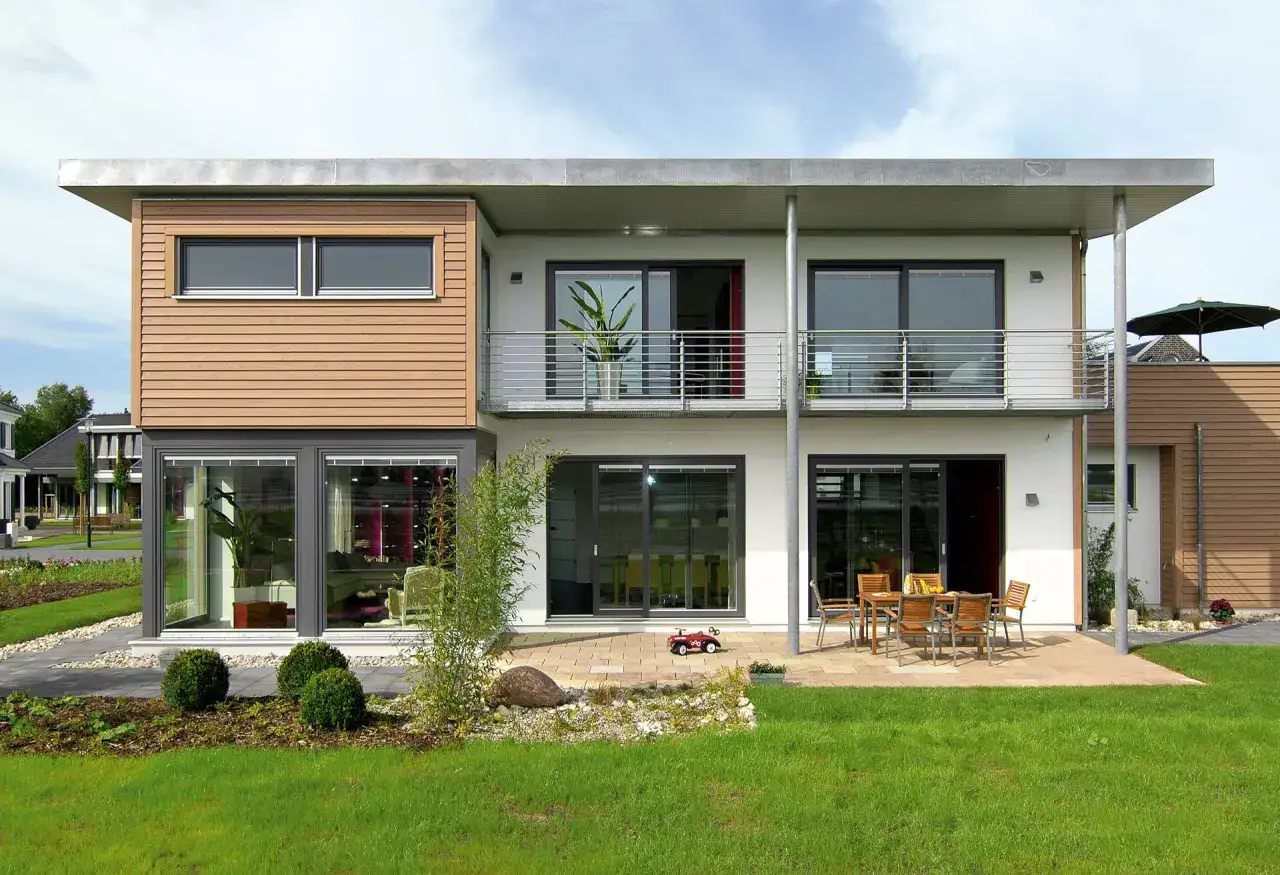 Modernes kleines Haus mit Holzverkleidung und einer gro&szlig;z&uuml;gigen Dachterrasse. Ein Garten mit Rasen und B&uuml;schen l&auml;dt zum Entspannen ein.