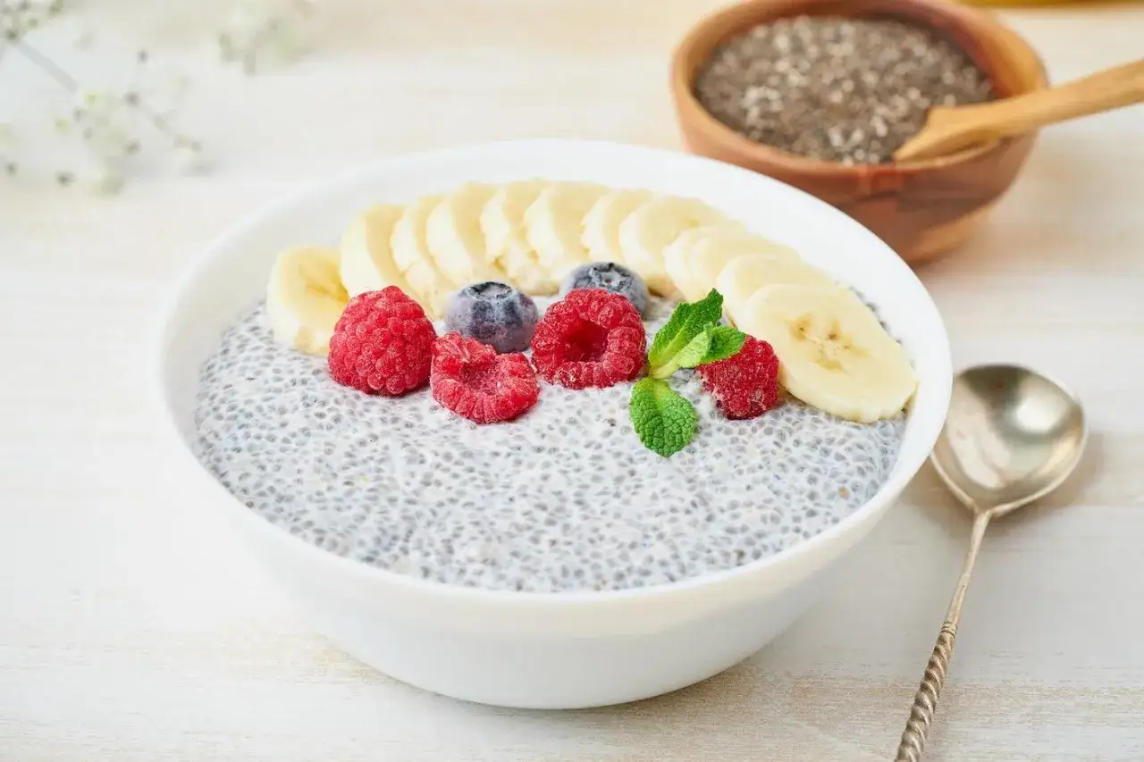 Un bol de pudding de graines de chia, garni de framboises, myrtilles et bananes. Parfait pour une femme enceinte cherchant un repas nutritif.