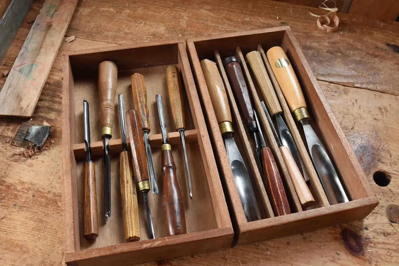 Boîte en bois remplie de gouges à bois de différentes tailles, prêtes pour le travail du bois.