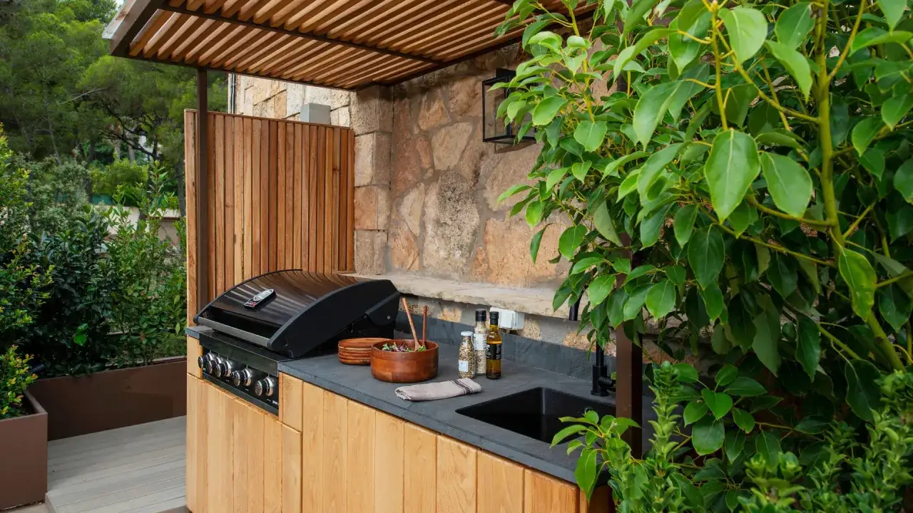 Cocina exterior moderna con parrilla, fregadero y encimera de piedra. Un rincón perfecto para disfrutar de quinchos modernos y reuniones al aire libre.