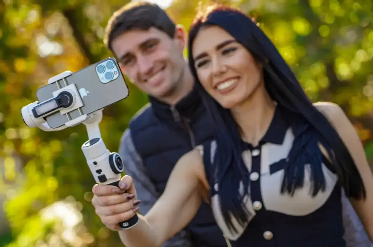 Para nagrywa filmik smartfonem zamontowanym na stabilizatorze. To właśnie **co to gimbal** – urządzenie, które zapewnia płynne ujęcia.