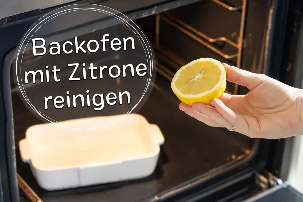 Backofen reinigen mit Zitrone: Eine Hand hält eine halbe Zitrone über eine leere Auflaufform im dunklen Backofen.