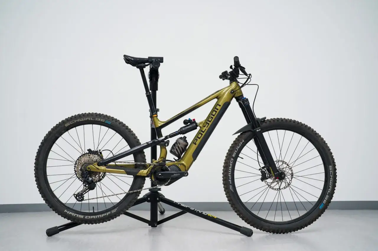 A gold Polygon electric mountain bike with a mullet setup (29er front, 27.5