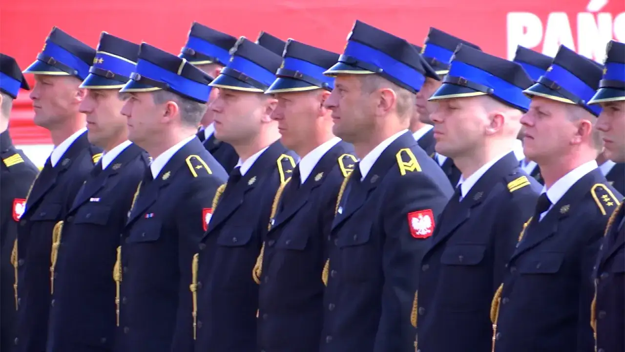 Uroczysta defilada strażaków w granatowych mundurach i charakterystycznych czapkach z niebieskim otokiem, zwanych potocznie capstrzyk.