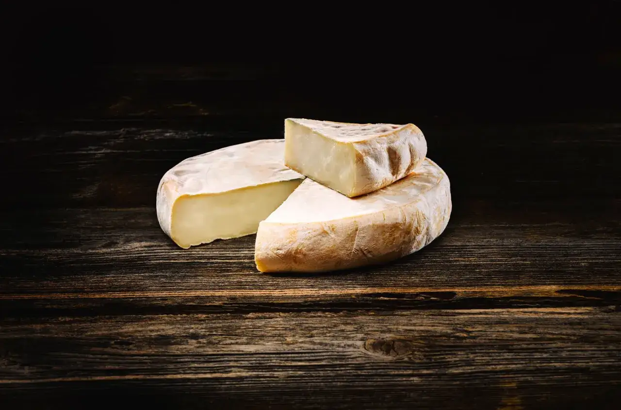 Un reblochon, fromage savoyard &agrave; p&acirc;te press&eacute;e non cuite, est pr&eacute;sent&eacute; sur un fond de bois sombre.