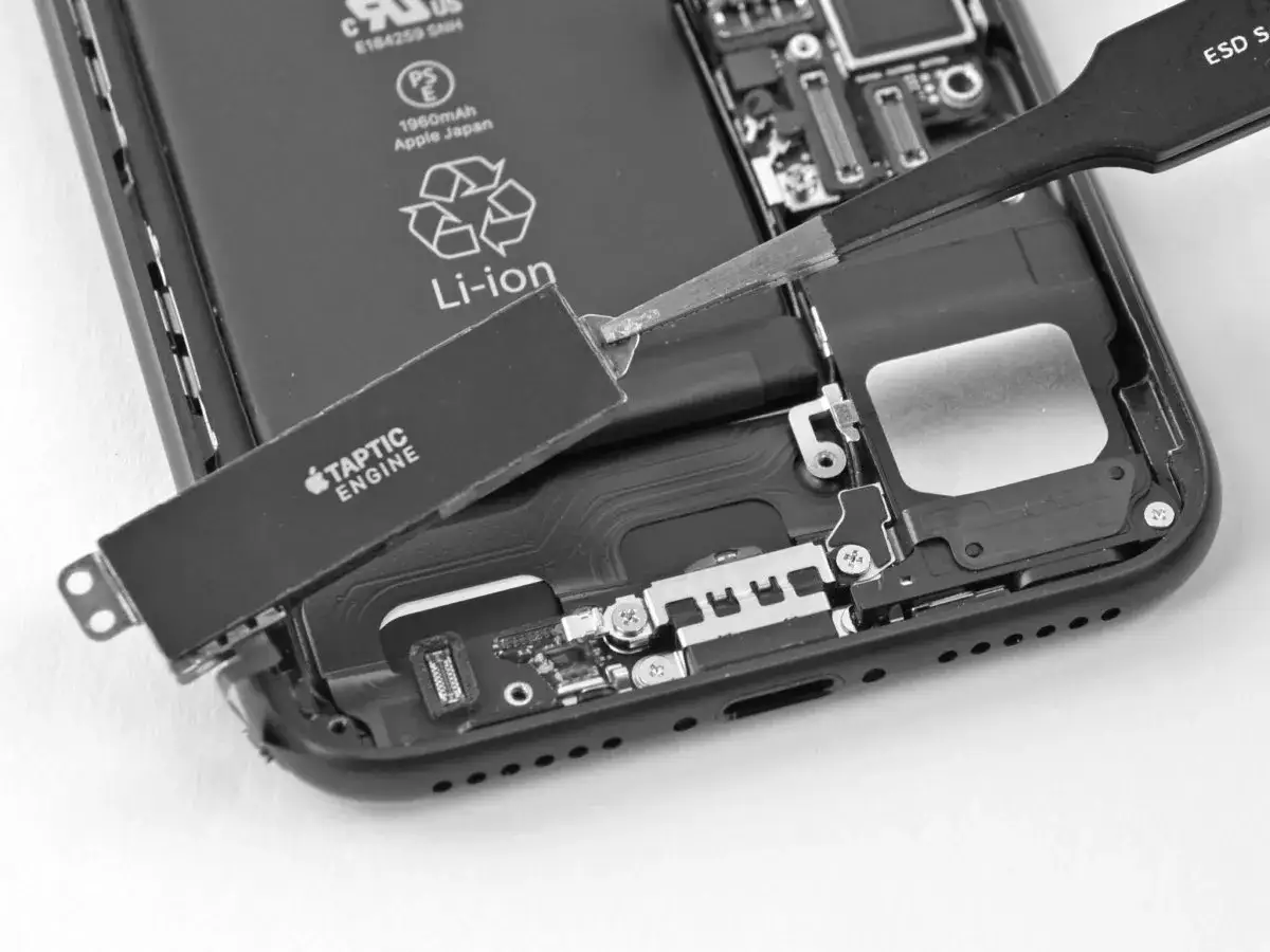 Naprawa telefonu, demontaż modułu haptyka Taptic Engine. Widać baterię Li-ion i wnętrze urządzenia.