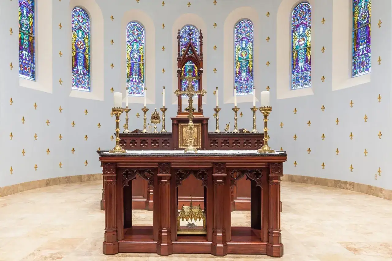 An altar in a church, with stained glass windows and ornate woodwork. This scene evokes the solemnity of liturgy, a formal religious ceremony, and the specific ritual of the Mass.