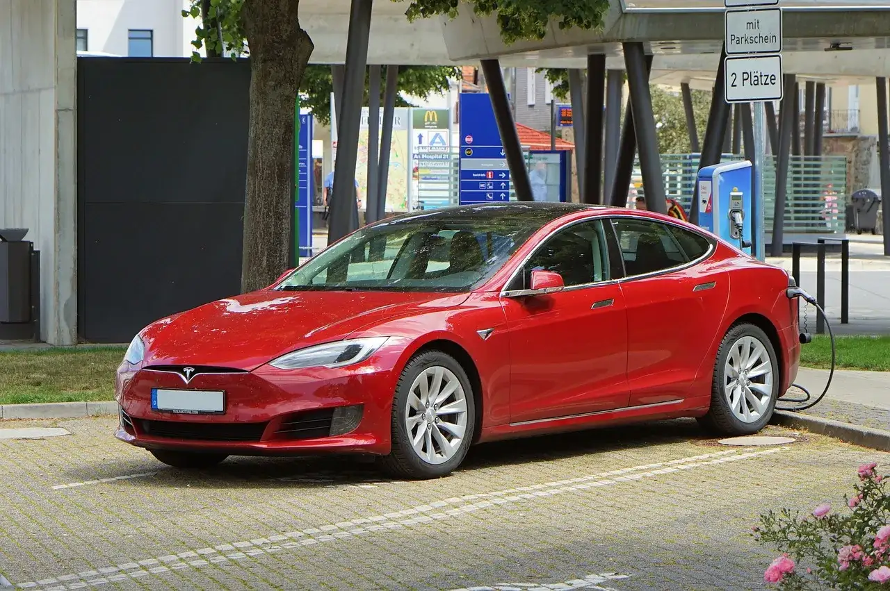 Czerwona Tesla Model S ładowana na parkingu. Zastanawiasz się, ile kosztuje Tesla Model S?