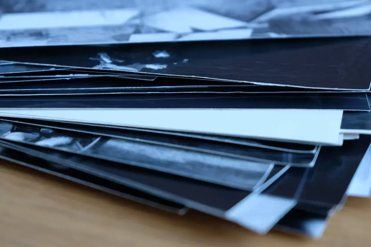 Stos czarno-białych odbitek fotograficznych, ukazujący różne rodzaje papieru, od błyszczącego po matowy.