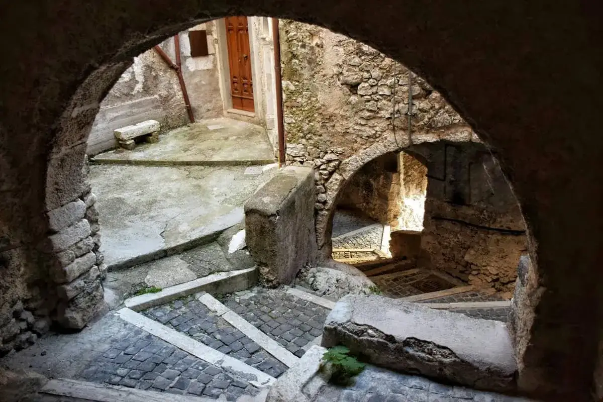 Antica scala di borgo con archi in pietra e ciottoli. Un invito a scoprire i segreti di un luogo senza tempo.