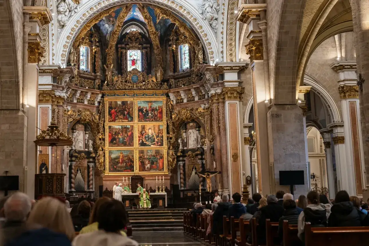 Wnętrze kościoła podczas uroczystości. W ołtarzu głównym trwa msza, a wierni uczestniczą w świętach katolickich.
