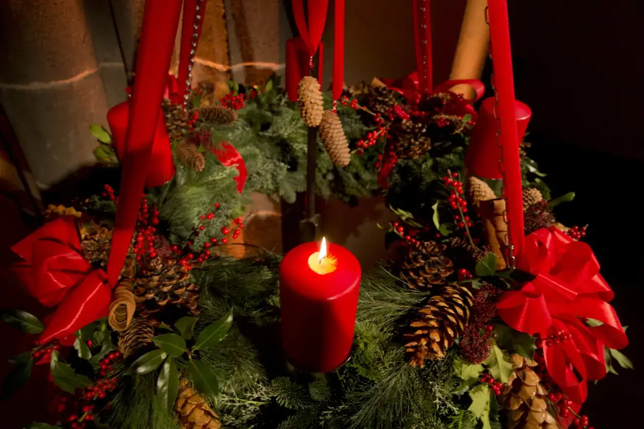Ein Adventskranz mit roten Kerzen, Tannenzweigen, Zapfen und Beeren. Die Stimmung erinnert an den 7. Januar, kurz nach Weihnachten.