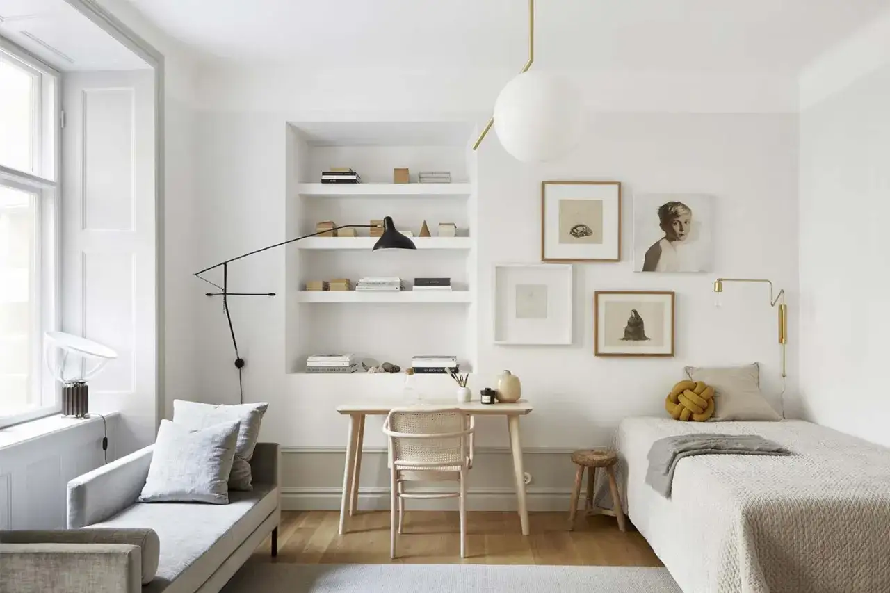 Camera ospiti idee: letto singolo, scrivania minimalista, divanetto grigio, libreria a muro e quadri d'autore.