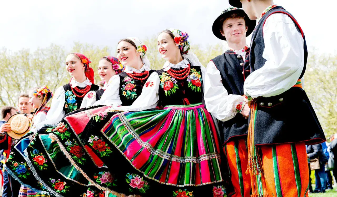 Młodzi ludzie w barwnych strojach ludowych, gotowi do poloneza. Kolorowy str&oacute;j z haftami i pasiakami.