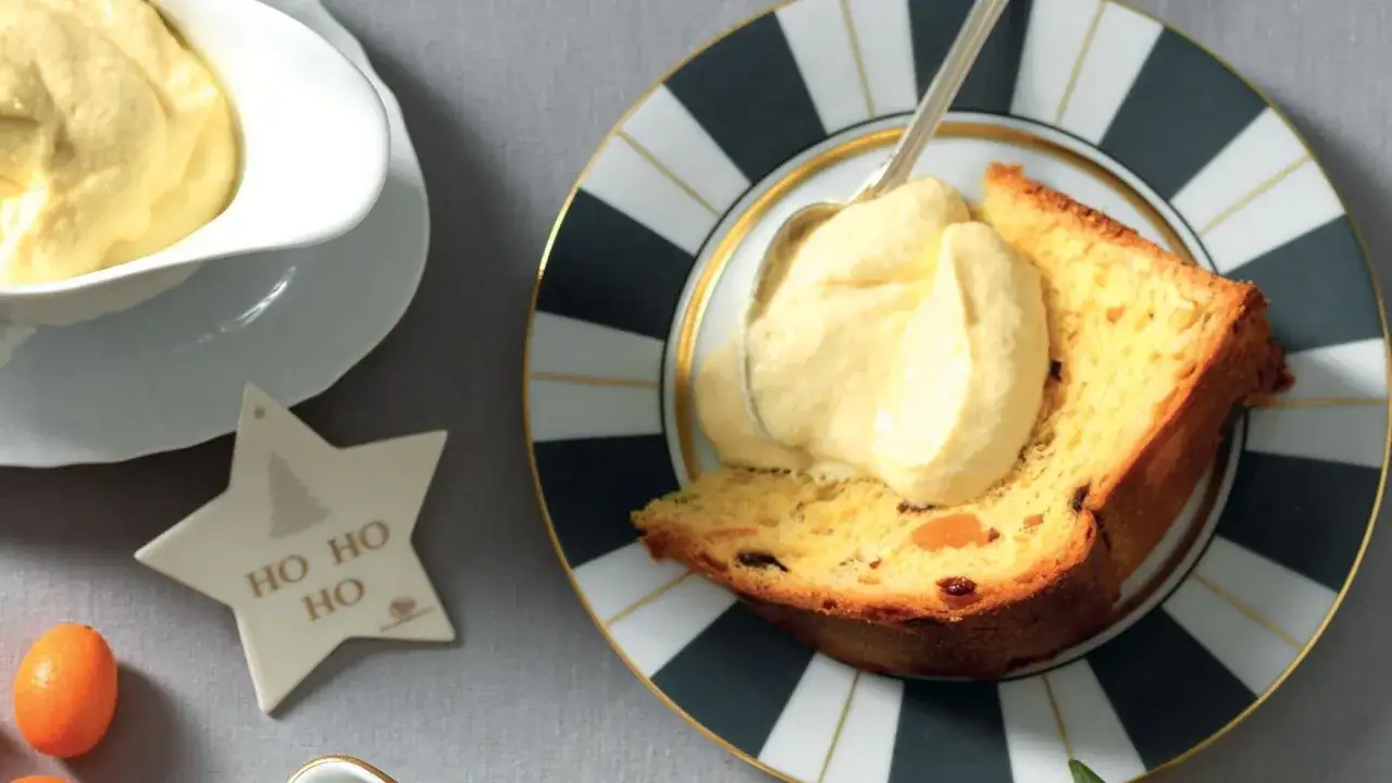 Una fetta di panettone con abbondante crema al mascarpone, servita su un piatto decorato.