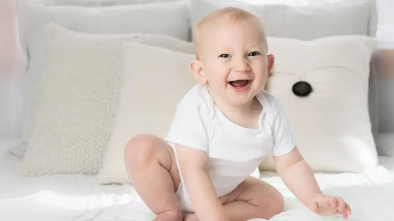 Ein lachendes Baby in Weiß, ein echtes Kind der Sonne. Elias' Bedeutung strahlt in seinem fröhlichen Gesicht.