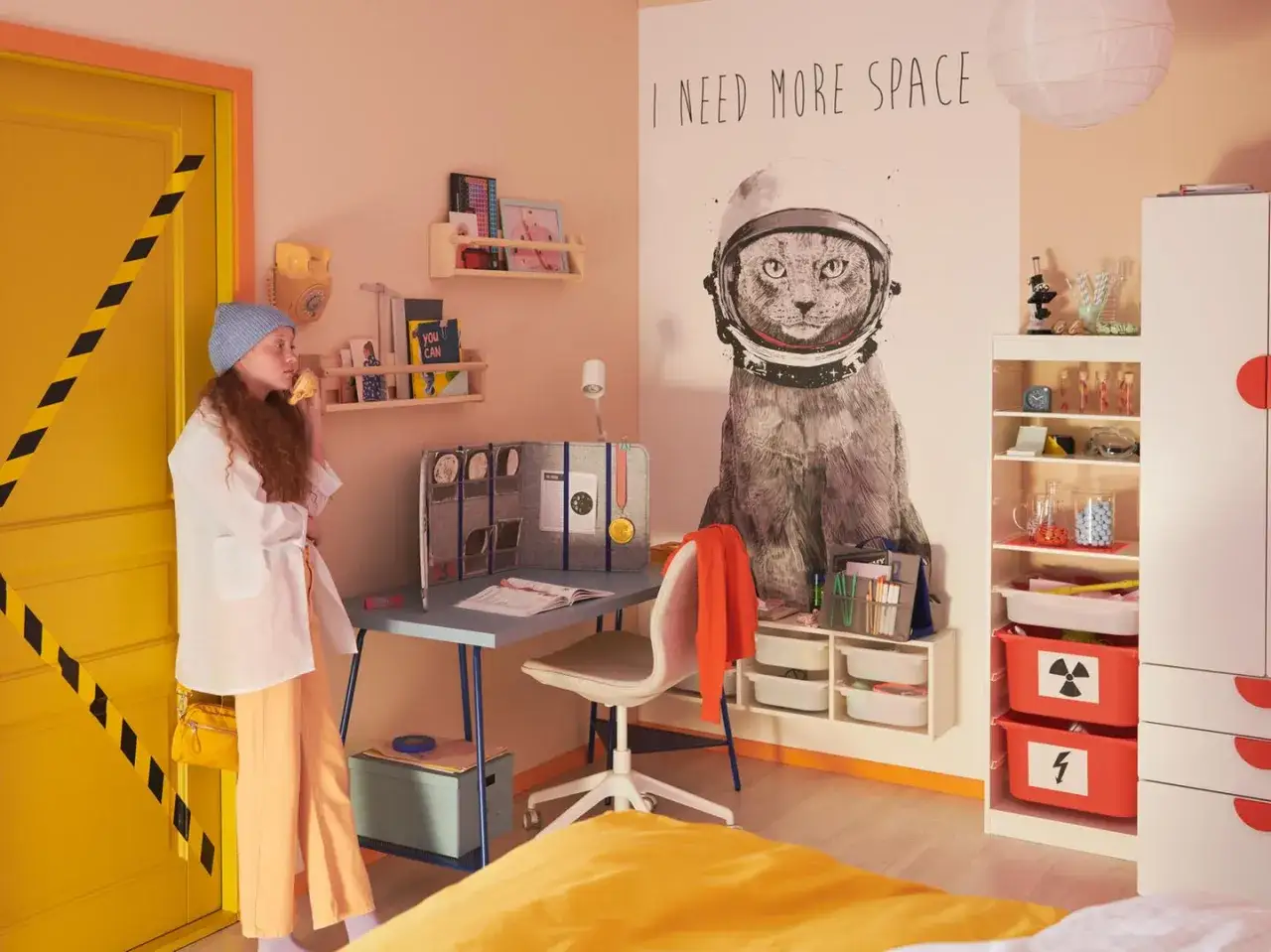 Coole Jugendzimmer Ideen: Ein M&auml;dchen im Weltraum-Outfit vor einem Schreibtisch mit Katzen-Poster.