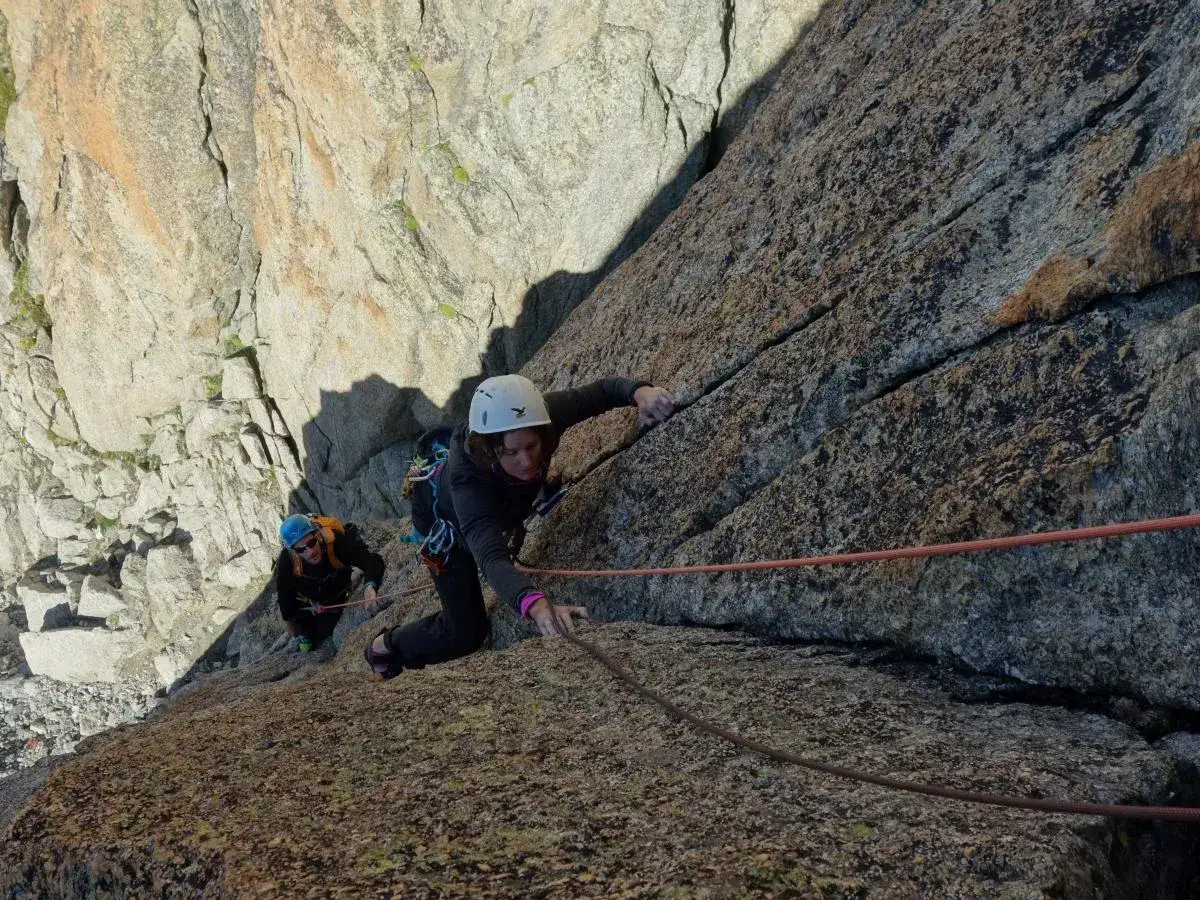 Deux alpinistes escaladent une paroi rocheuse abrupte, défiant les hauteurs vertigineuses des **blocs des Alpes**.