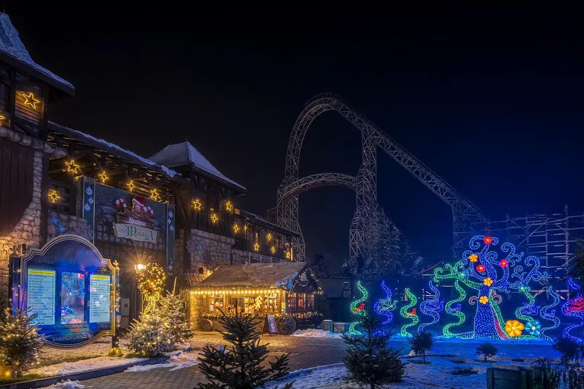 Magiczna noc w Energylandii zimą. Śnieg, choinki, świąteczne iluminacje i kolejka górska tworzą bajkowy klimat.