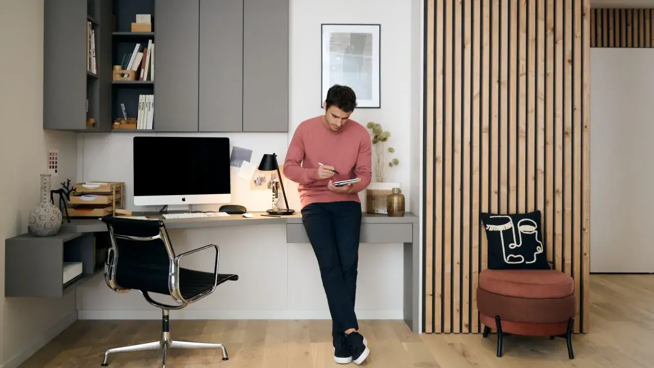 Un homme utilise une tablette dans un bureau moderne. L'espace de travail est bien équipé, rappelant l'obligation employeur fournir ordinateur pour le télétravail.