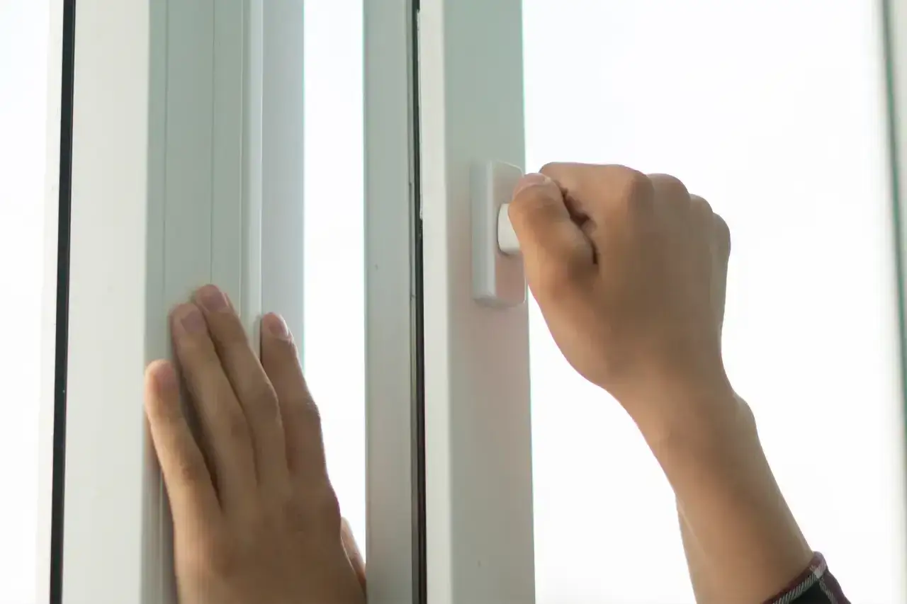 Manos ajustan la ventana para que entre aire.
