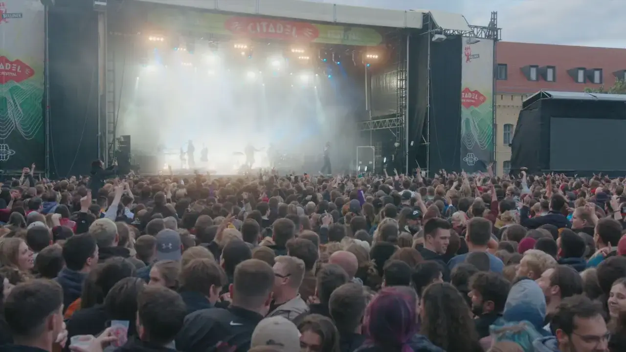Ein riesiges Publikum feiert heute in Berlin beim Citadel Music Festival. Die Band spielt auf der B&uuml;hne, w&auml;hrend die Menge jubelt und Fotos macht.