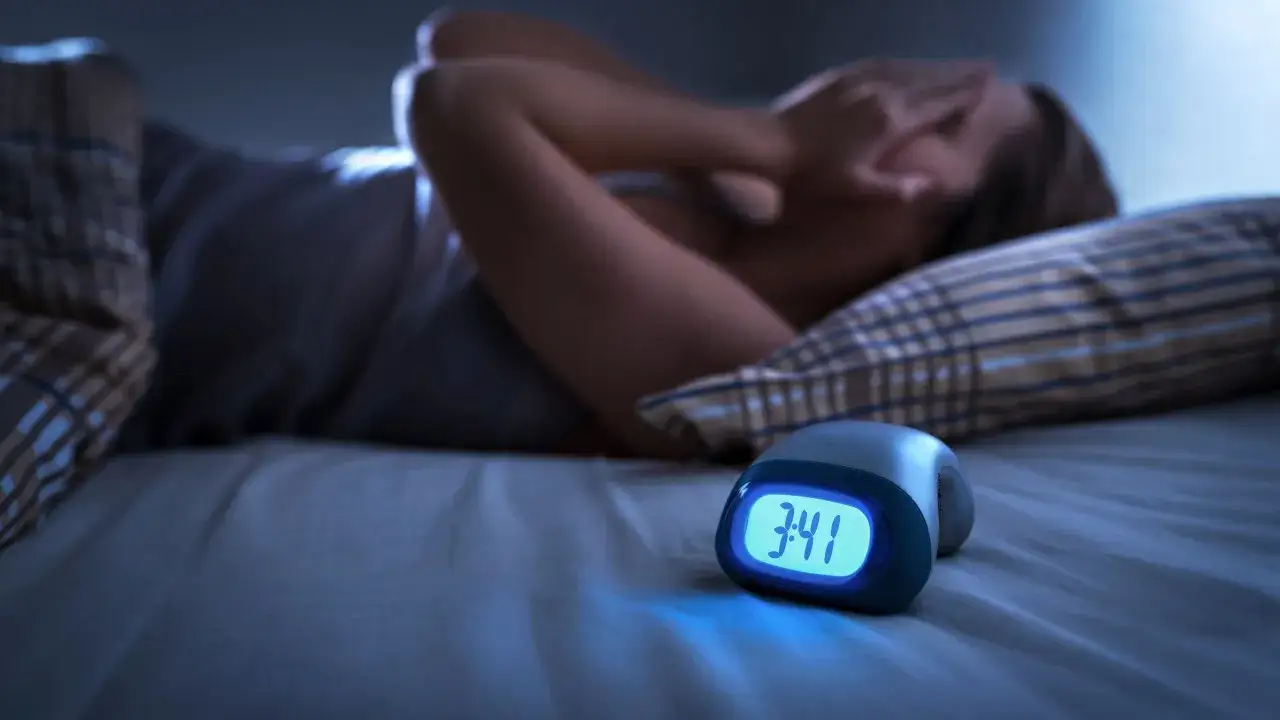 Une personne souffre d'insomnie, le stress du travail l'empêche de dormir. L'horloge affiche 3h41.