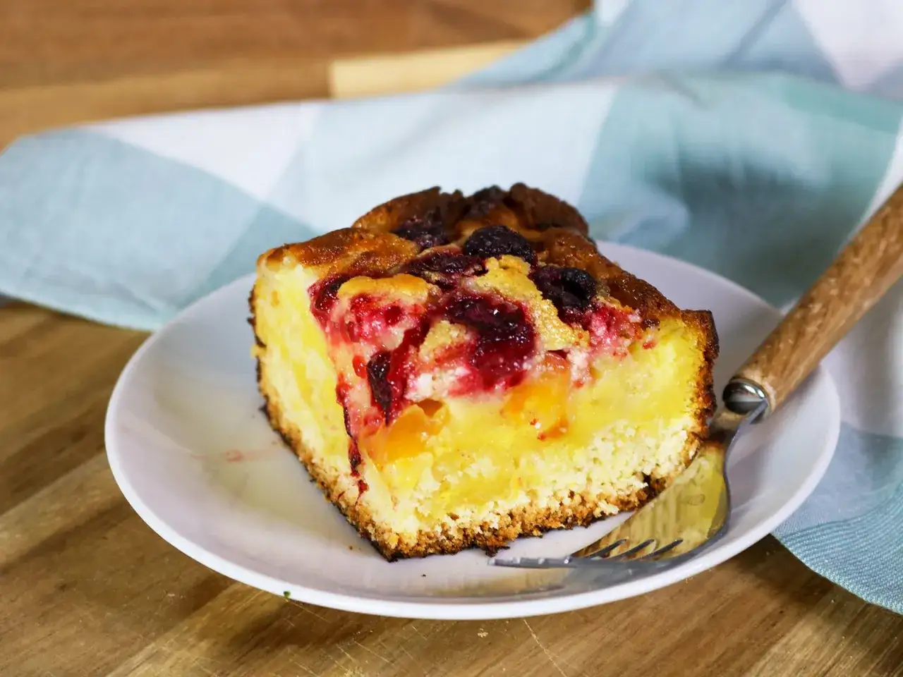 Ein saftiges Stück Spiegeleikuchen mit Quark und Beeren, bereit zum Genießen.