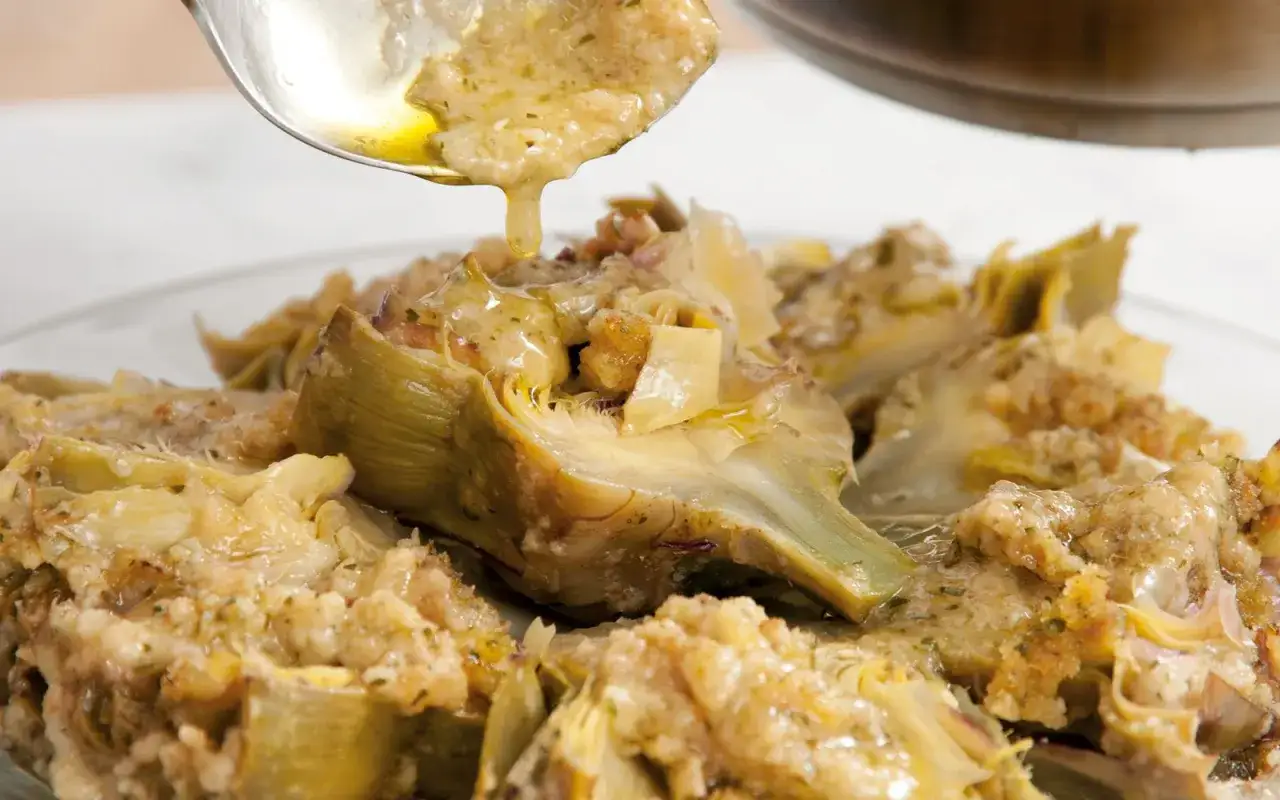 Carciofi alla romana succulenti, conditi con un sughetto dorato e profumato, pronti per essere gustati.