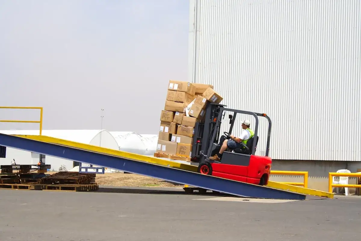 Gabelstapler entladen einen LKW mit vielen Kartons auf einer Rampe.