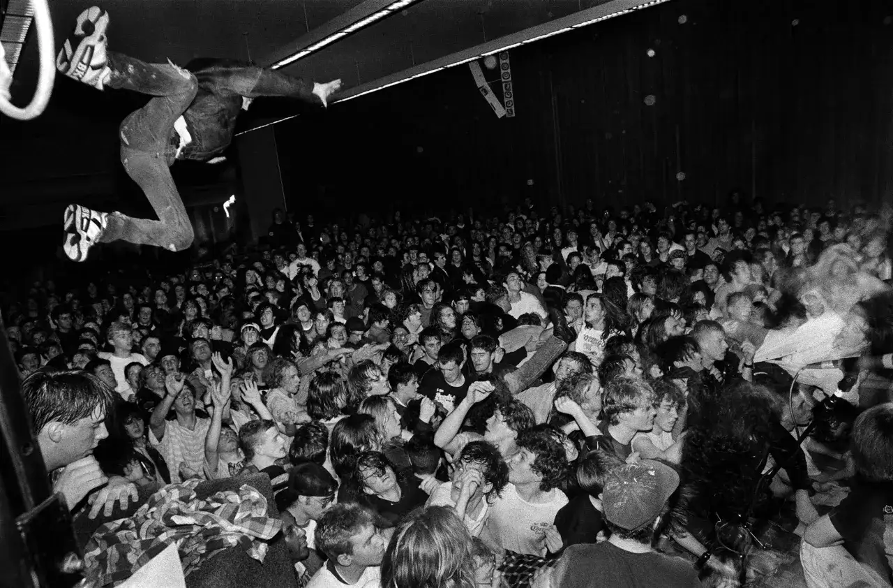 A crowd surges as a performer leaps mid-air. Capturing such raw energy is key to learning how to become a concert photographer.