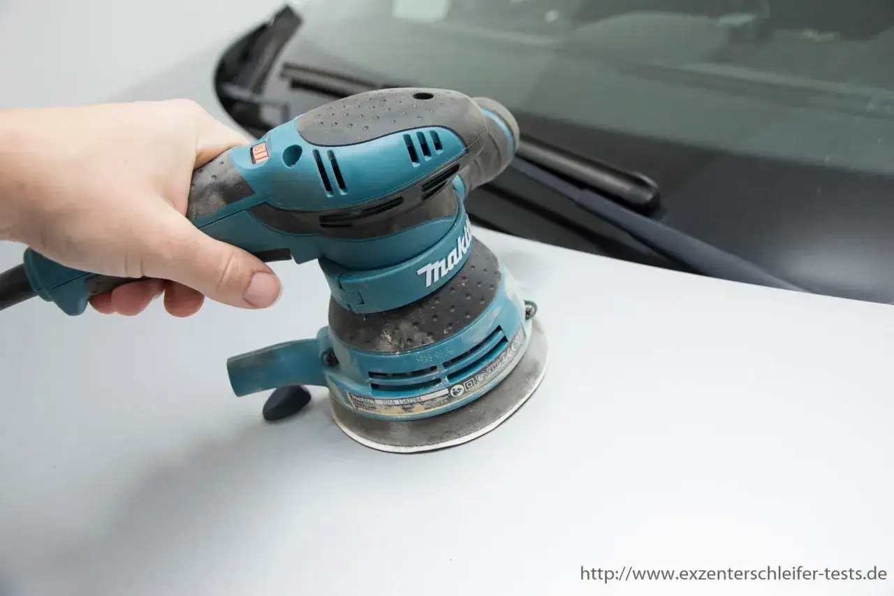 Hand hält einen Exzenterschleifer, bereit zum polieren des Autos.