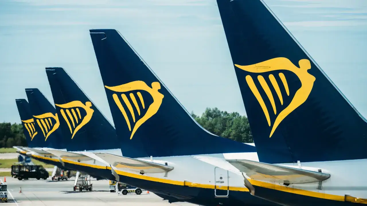 Rzędy samolotów Ryanair na płycie lotniska. Złote logo z aniołem na ciemnogranatowych ogonach zapowiada podróże z Malta Air.