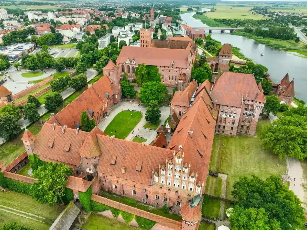 Malbork zwiedzanie za darmo? To marzenie! Zobacz ogromny zamek z lotu ptaka, z czerwonymi dachami i zielonymi dziedzińcami.