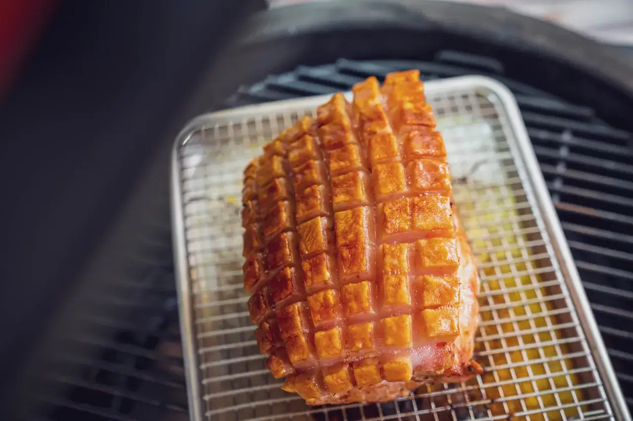 Ein knusprig gegrillter Schweinebauch auf einem Rost, bereit zum Genießen. Die Schwarte ist perfekt karamellisiert.