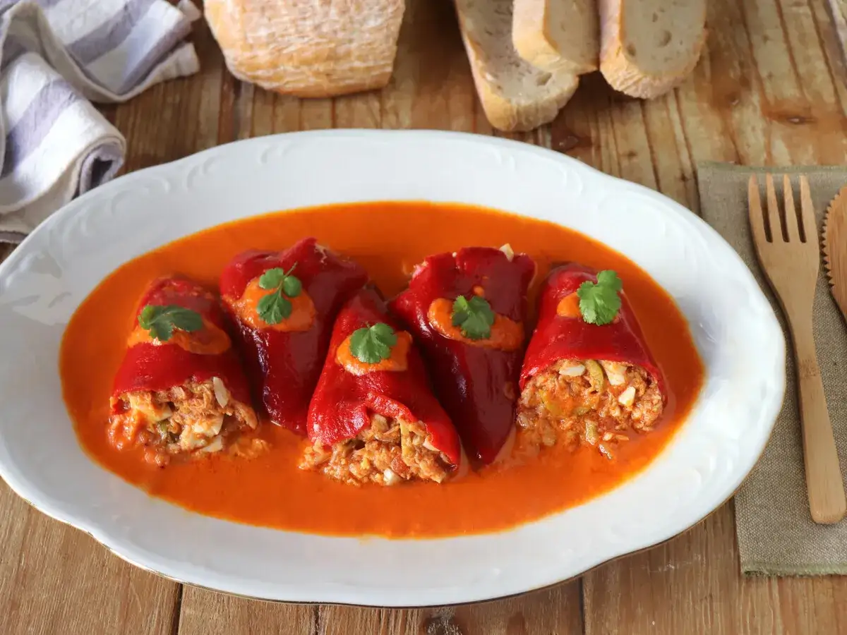 Pimientos del piquillo rellenos de at&uacute;n y huevo, servidos en una salsa roja cremosa.