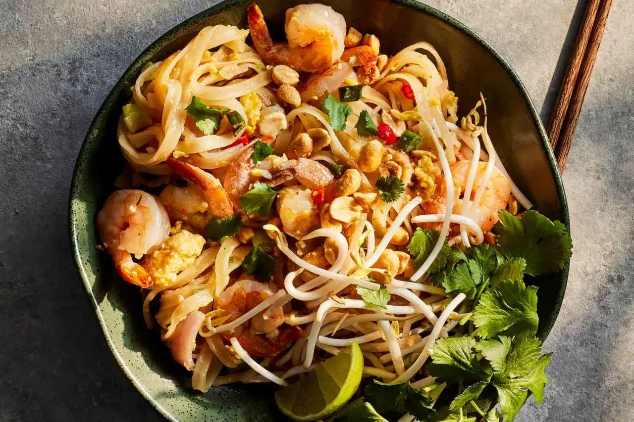 Un delicioso plato de **receta pad thai** con camarones, fideos de arroz, brotes de soja, cacahuetes y cilantro fresco.