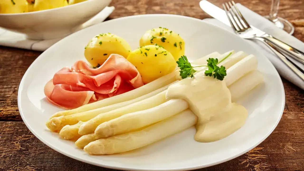 Białe szparagi z szynką, ziemniakami i sosem. Unikaj przyczyn rozpadania się emulsji w domowym sosie bernaise, by danie wyglądało apetycznie.