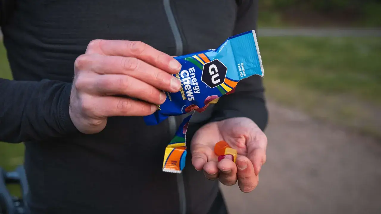Mains tenant des bonbons énergétiques GU pour l'alimentation marathon. Un coureur se ravitaillant en chemin.