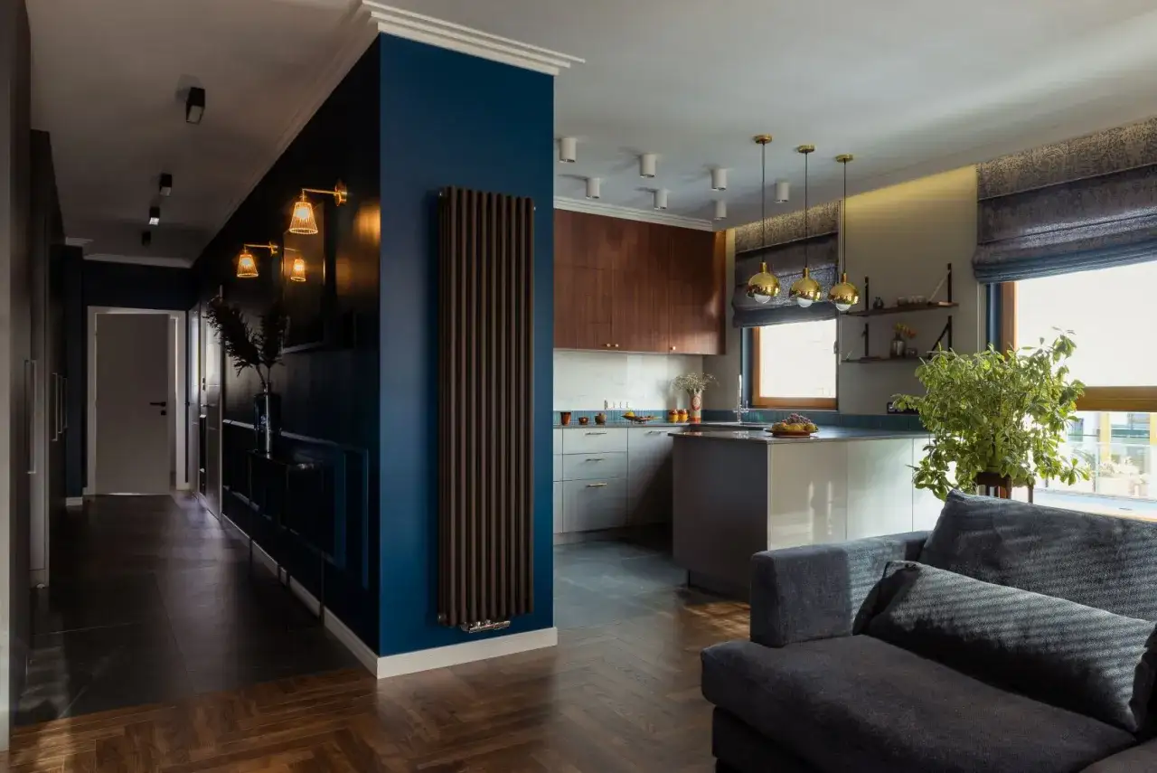 Nowoczesny salon z ciemną ścianą, kuchnią i wygodną kanapą.