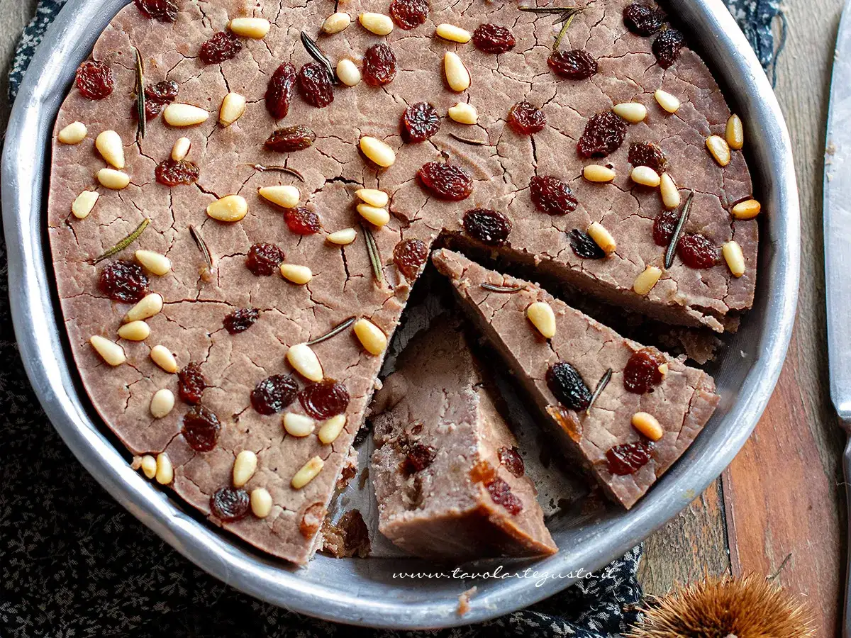 Castagnaccio con latte, un dolce rustico e profumato, guarnito con pinoli, uvetta e rosmarino.