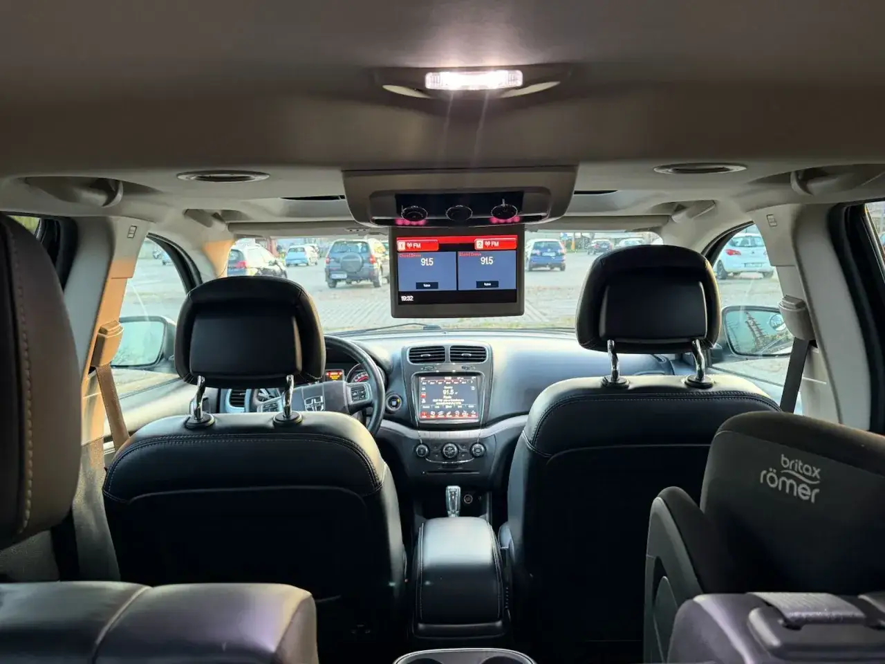 Wnętrze Dodge Journey 3.6 z ekranem multimedialnym i fotelikiem dziecięcym.