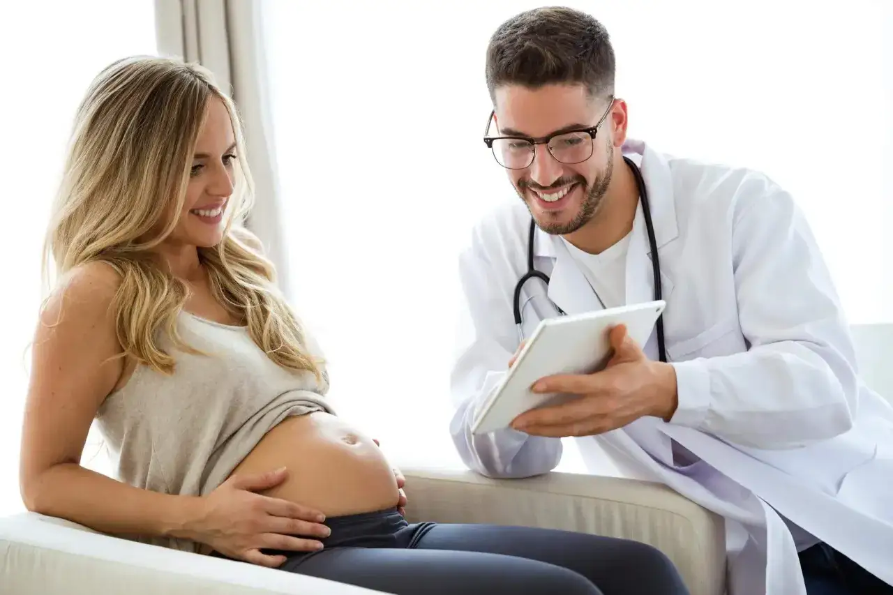 Lekarz omawia z ciężarną pacjentką kwestię amoksycyliny w ciąży, pokazując coś na tablecie.